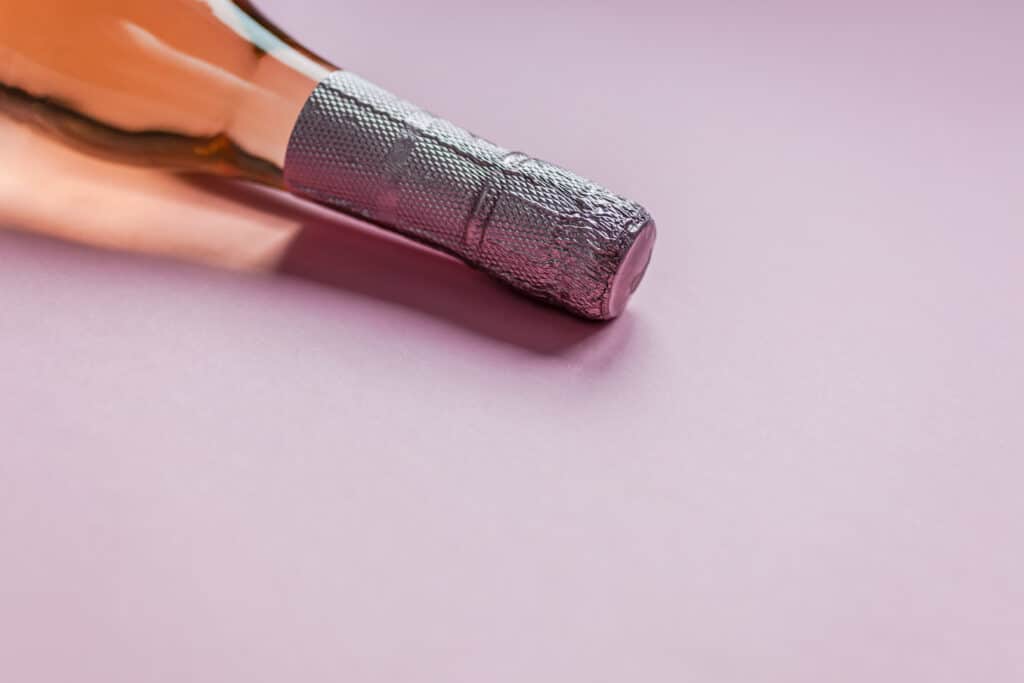 Bottle of rose champagne wine in minimal composition on pink background with copy space. Natural light. Template for tasting, degustation invitation card. Side view