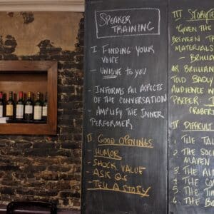 Speaker training tips on blackboard with wine display.