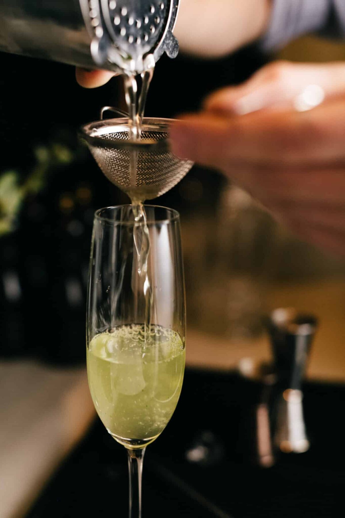 Pouring cocktail through strainer into glass