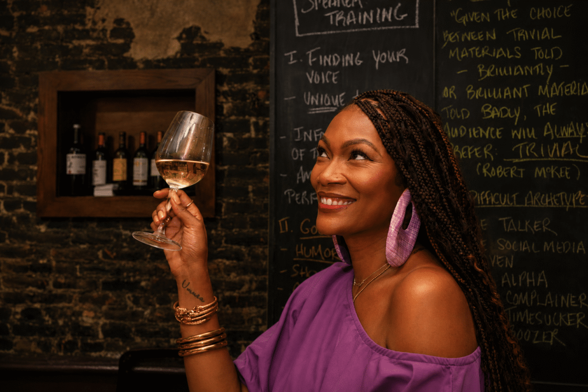 Tahiirah Habibi holding glass of white wine smiling